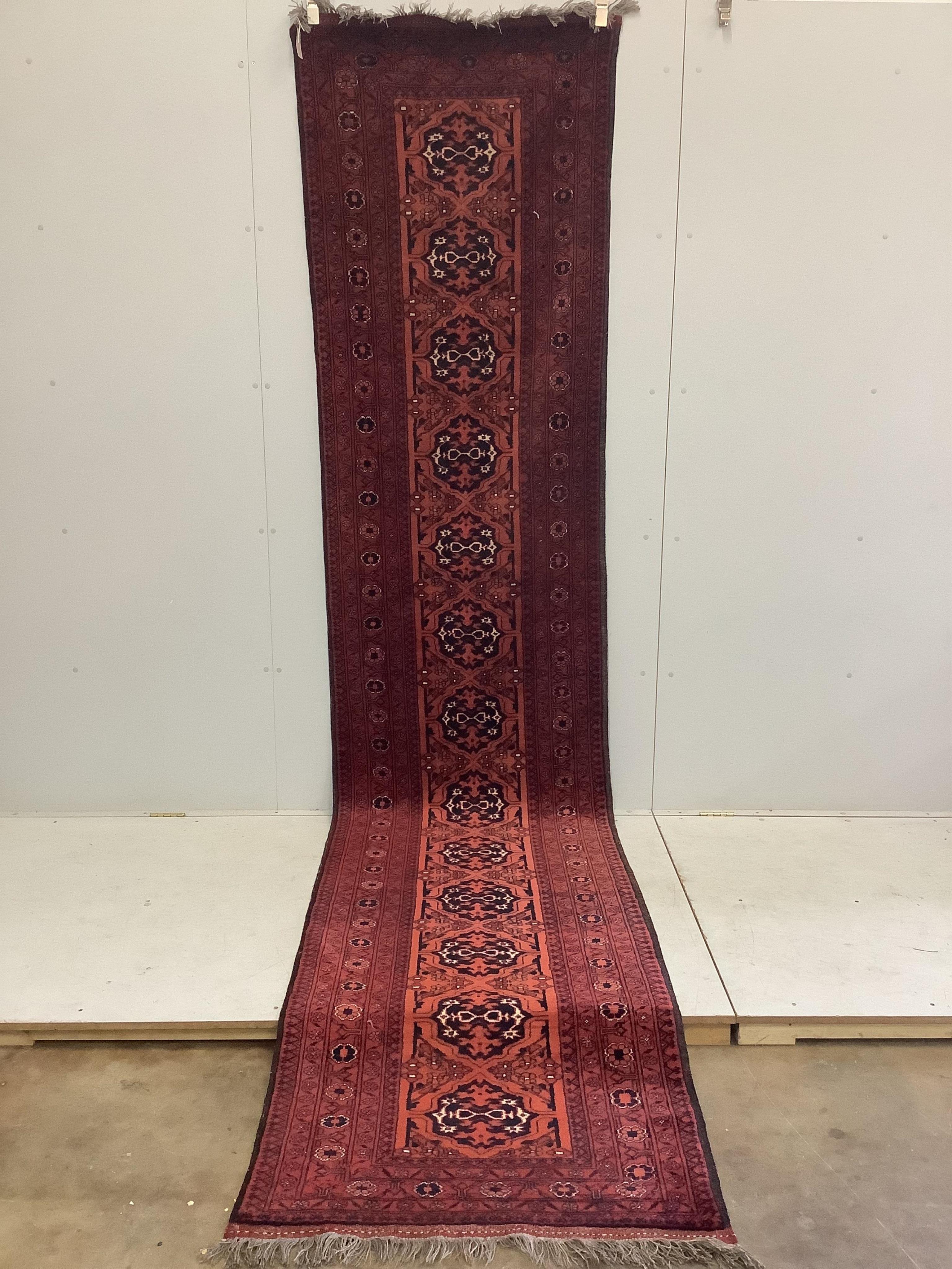 An Afghan red ground runner, approximately 400 x 86cm. Condition - fair